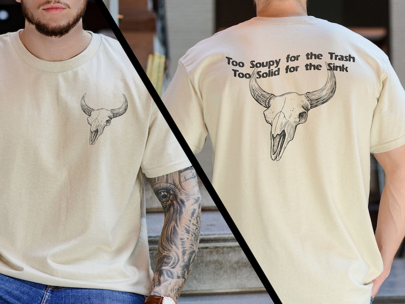 May include: A beige t-shirt with a skull graphic on the front and the text "Too Soupy for the Trash Too Solid for the Sink" on the back.