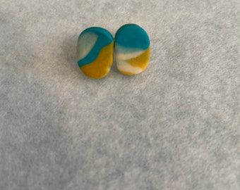 May include: A pair of oval-shaped earrings with a blue, white, and yellow abstract swirl pattern.