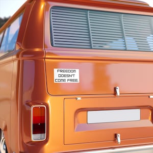 May include: A vintage orange van with a white sticker on the back that reads "FREEDOM DOESN'T COME FREE."