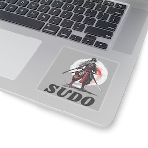 May include: A sticker featuring a black and white illustration of a samurai warrior holding two swords. The warrior is standing in front of a red circle with a white background. The text "SUDO" is printed below the image.