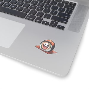 May include: A colorful sushi roll sticker with a happy face, tongue sticking out, and salmon topping. The sticker is on a red mat, placed on a laptop surface. The sushi roll is a fun, cartoon-style design.