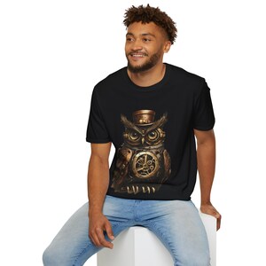 May include: A black t-shirt featuring a graphic of a steampunk owl wearing a top hat. The owl is constructed from gears and other metal components.