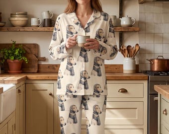 May include: A two-piece pajama set featuring a long-sleeved button-down shirt and matching pants, both decorated with a repeating pattern of dogs wearing scarves. The fabric is off-white with brown and blue illustrations of the canine figures.