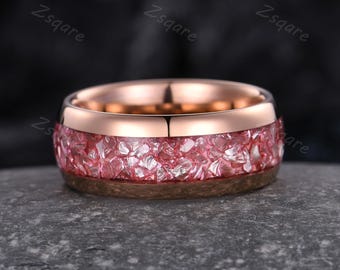 May include: A rose gold tungsten carbide ring with a pink and white crushed glass inlay.