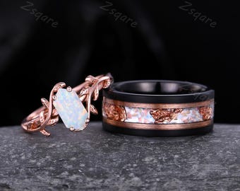 Könnte beinhalten: Ein Paar Eheringe. Der Damenring ist aus Roségold und hat ein filigranes Astdesign mit einem weißen Opal-Edelstein. Der Herrenring ist schwarz mit einem Roségoldband und weißen Opal-Akzenten.