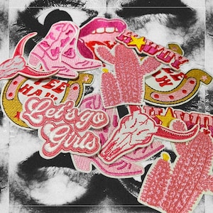 Può includere: Una collezione di toppe da stirare ricamate rosa con vari disegni, tra cui un ferro di cavallo, un cactus, un teschio, uno stivale e il testo "Let's go girls".