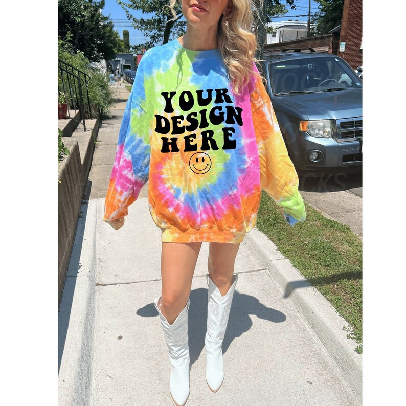 May include: A tie-dye sweatshirt with the text "YOUR DESIGN HERE" and a smiley face. The sweatshirt is a bright mix of pink, orange, yellow, blue, and green.