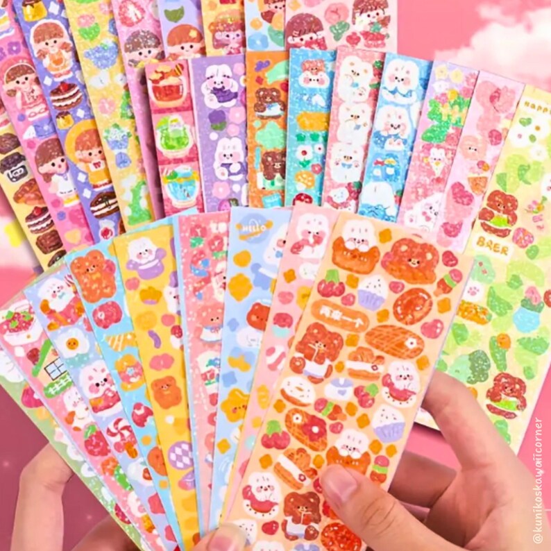 Op de afbeelding: Een verzameling kleurrijke sticker vellen met verschillende schattige illustraties. Ontwerpen omvatten beren, konijntjes, cakes en andere voedingsmiddelen. De stickers zijn in roze, blauw, geel en groen, met een kawaii-esthetiek.