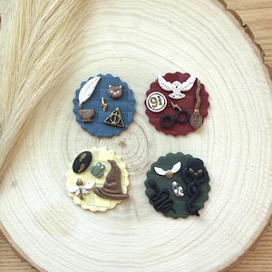 May include: Four decorative, round, themed toppers with various designs. One features a feather, a bear, and a lightning bolt. Another has an owl, scissors, and a broom. A third has a hat and a frog. The last has a snake and a creature.