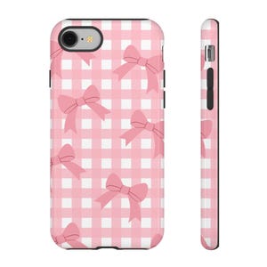 May include: A phone case with a pink gingham pattern and pink bow accents. The case is shown from the front and side, showcasing the design's wrap-around coverage. The case is designed to fit a smartphone.
