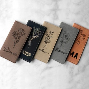 May include: Six personalized leather card holders with floral designs and names engraved on each. The holders are in various colors, including brown, black, beige, gray, and orange.