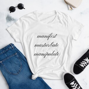 May include: White t-shirt with the words "manifest", "masturbate", and "manipulate" printed in black cursive.