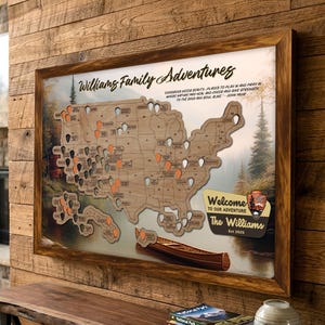 May include: Wooden map of the United States with family adventure pins. The map is framed and includes the text "Williams Family Adventures" and "Welcome to our Adventure". A canoe is depicted at the bottom.