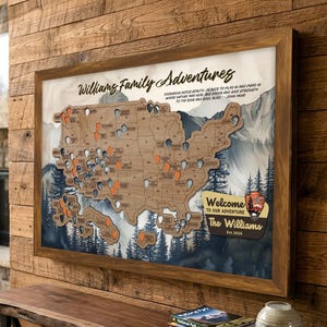 May include: Wooden framed map of the United States with pin markers, titled "Williams Family Adventures." The map features a watercolor mountain and forest background. Includes the text "Welcome to our adventure" and "The Williams Est 2025."