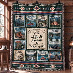 May include: A woven throw blanket featuring a dark green background with a central cream-colored panel displaying the text Lily & Grant EST. 2021. Surrounding the center are twelve rectangular postage stamp-style illustrations of outdoor scenes, hiking gear, and mountains with various adventure-themed captions.
