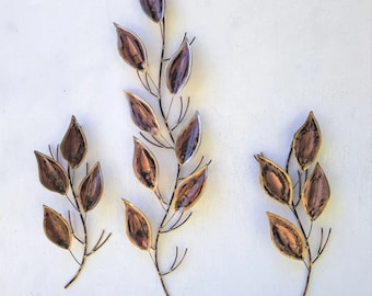 May include: Three metal wall sculptures in the shape of leafy branches with brown and gold leaves.