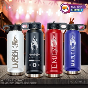 May include: Four stainless steel water bottles with personalized names and music-themed designs. The bottles are white, black, red, and blue. Each bottle has a flame design and a different music-related icon. The text "WE CAN ENGRAVE NAME/DESIGN/TRACK CODE" is at the bottom of the image.