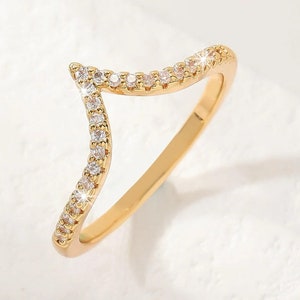 May include: A gold ring with a V-shaped design accented with small clear stones.
