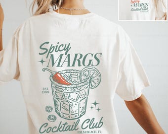May include: An off-white short-sleeve t-shirt featuring a graphic on the back with the text Spicy MARGS Cocktail Club, EST. 1988, and Palm Beach, FL. The design includes a cocktail glass with a chili pepper, lime slice, and stars.