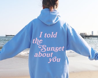 May include: A light blue hoodie with the text "I told the sunset about you" printed in pink on the back.