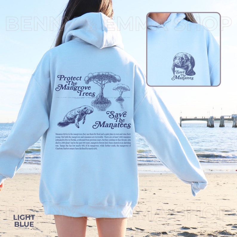 May include: Light blue hooded sweatshirt with a manatee and mangrove tree design. The back of the sweatshirt has the text "Protect the Mangrove Trees" and "Save the Manatees" with a short description about manatees and mangroves. The front of the sweatshirt has a smaller manatee design with the text "Save the Manatees".