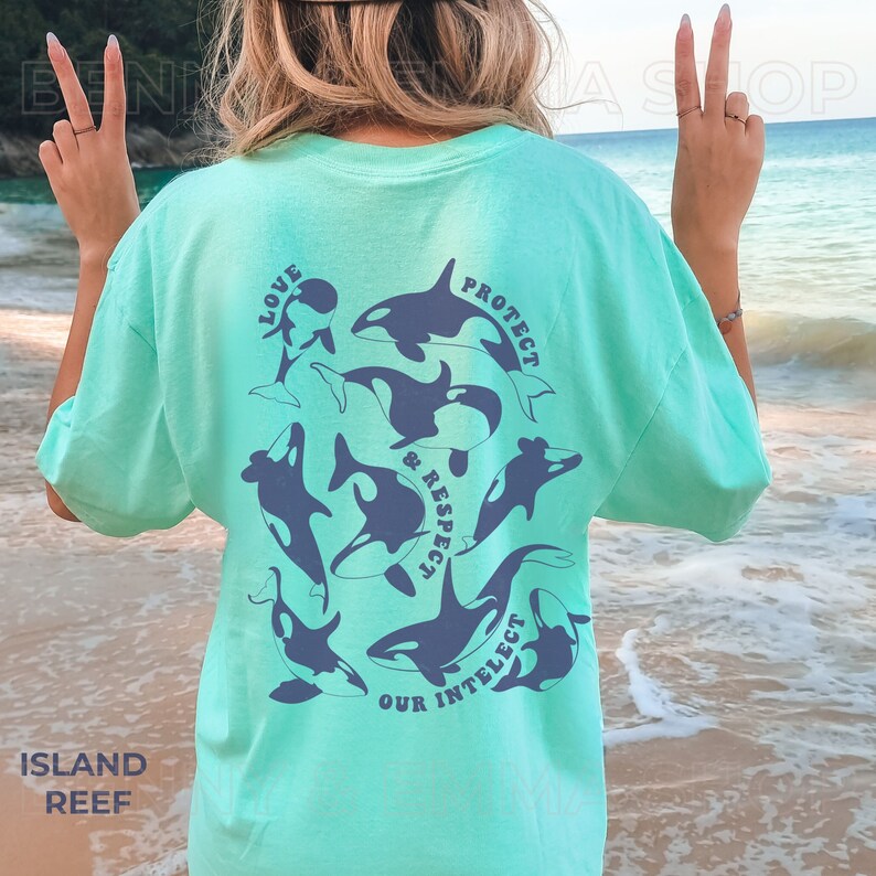 May include: A turquoise blue t-shirt with a graphic of orcas and the text "Love, Protect & Respect Our Intellect" printed on the back.