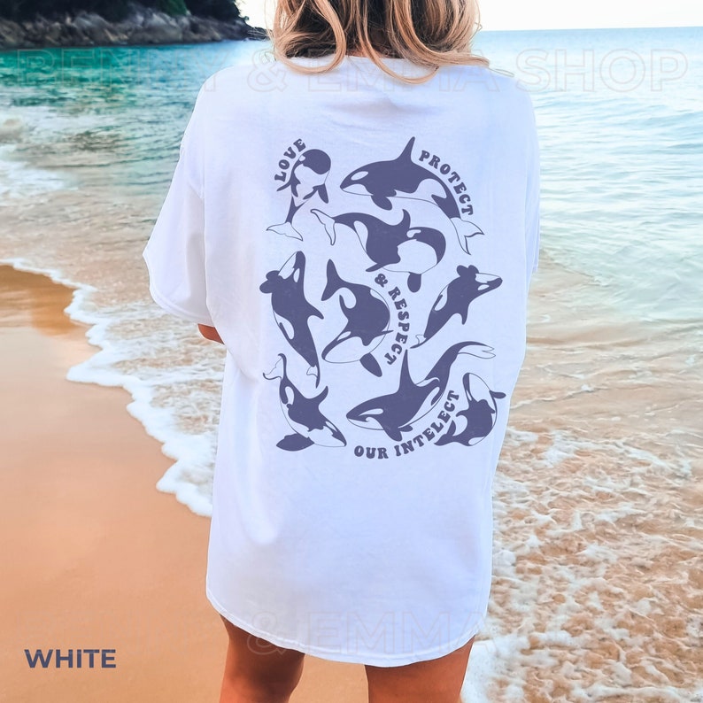 May include: White t-shirt with a graphic of orcas and the text "Love, Protect & Respect Our Intellect" printed on the back.