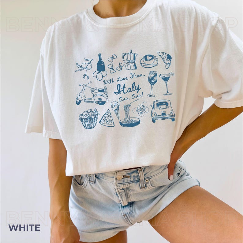 May include: White t-shirt featuring a blue graphic print of Italian icons, including a scooter, pizza, pasta, wine, and the text "With Love From Italy Ciao, Ciao!"