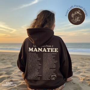 K&ouml;nnte beinhalten: Ein brauner Hoodie mit einem wei&szlig;en Grafikdruck auf der R&uuml;ckseite, der "Life Lessons From A Manatee" sagt und 44 Lebenslektionen auflistet. Der Hoodie hat eine vordere linke Tasche und der Text "Front Left Pocket Design" ist in der oberen rechten Ecke des Bildes gedruckt.