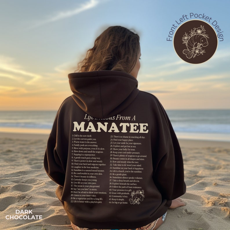 K&ouml;nnte beinhalten: Ein brauner Hoodie mit einem wei&szlig;en Grafikdruck auf der R&uuml;ckseite, der "Life Lessons From A Manatee" sagt und 44 Lebenslektionen auflistet. Der Hoodie hat eine vordere linke Tasche und der Text "Front Left Pocket Design" ist in der oberen rechten Ecke des Bildes gedruckt.