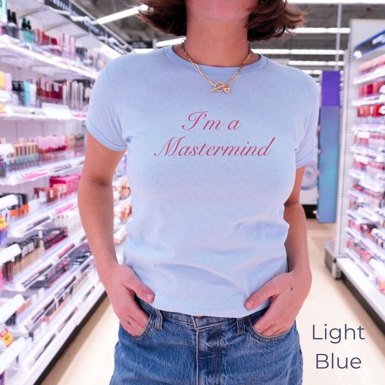 May include: A light blue t-shirt with the text "I'm a Mastermind" printed in pink on the front.