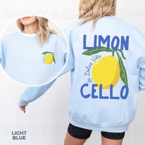 May include: Light blue sweatshirt with a lemon graphic and the text "LIMON La Dolce Vita CELLO" printed on the back.