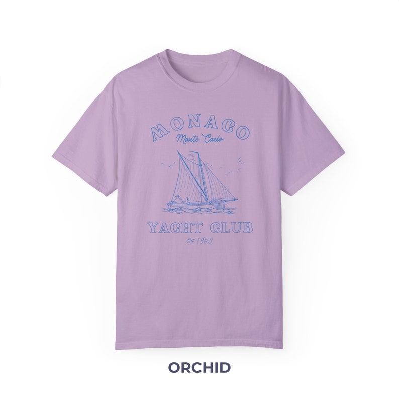 Peut inclure: Un t-shirt lavande avec un graphique bleu d'un voilier et le texte "MONACO Monte Carlo YACHT CLUB Est 1953"