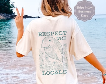 Peut inclure: T-shirt ivoire avec un graphique de lamantin et le texte "Respect the Locals" imprimé au dos.