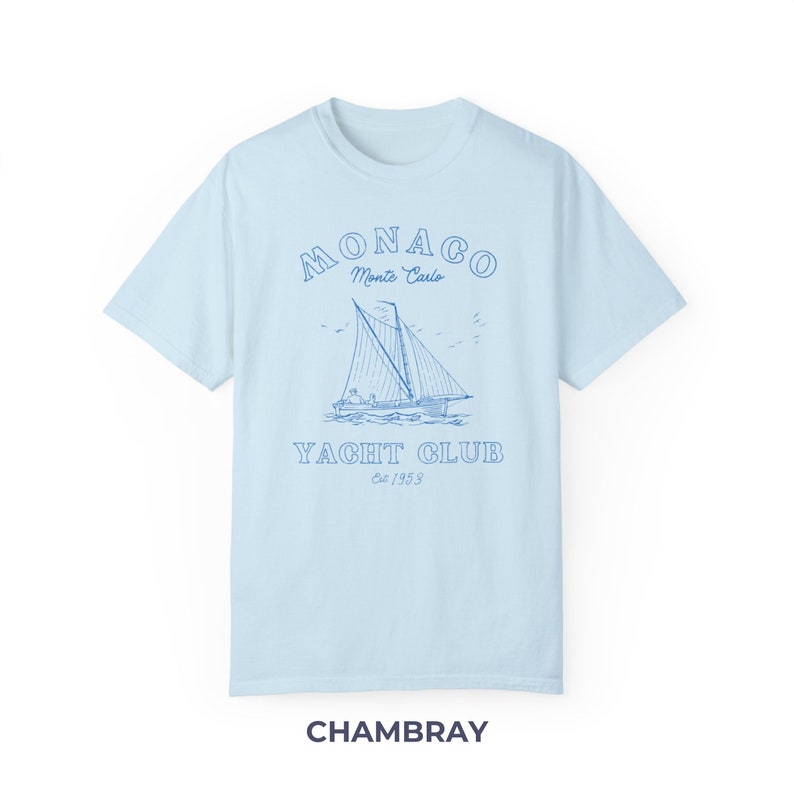Peut inclure: Un t-shirt bleu clair avec un graphique de voilier et le texte "MONACO Monte Carlo YACHT CLUB Est 1953" en bleu.