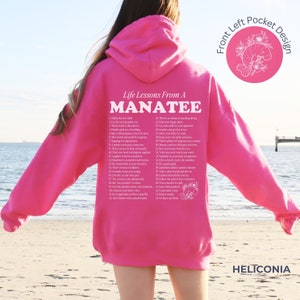 K&ouml;nnte beinhalten: Rosaer Hoodie mit einem wei&szlig;en Grafikdruck einer Liste von Lebenslektionen von einem Seekuh. Der Text enth&auml;lt S&auml;tze wie "Chill the vibe", "Let the current guide you", "There's no shame in making all day" und "Go big or go home".