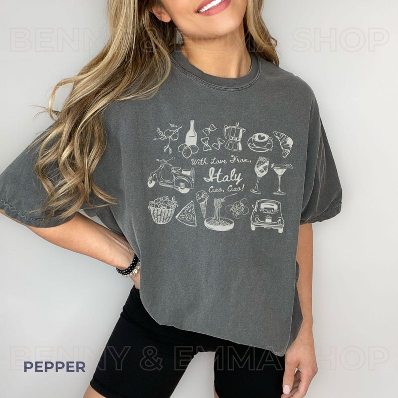 May include: A grey cropped t-shirt with a white graphic design featuring Italian icons such as a Vespa scooter, pizza, pasta, and wine. The text on the shirt reads "With love from... Italy Ciao, Ciao!"