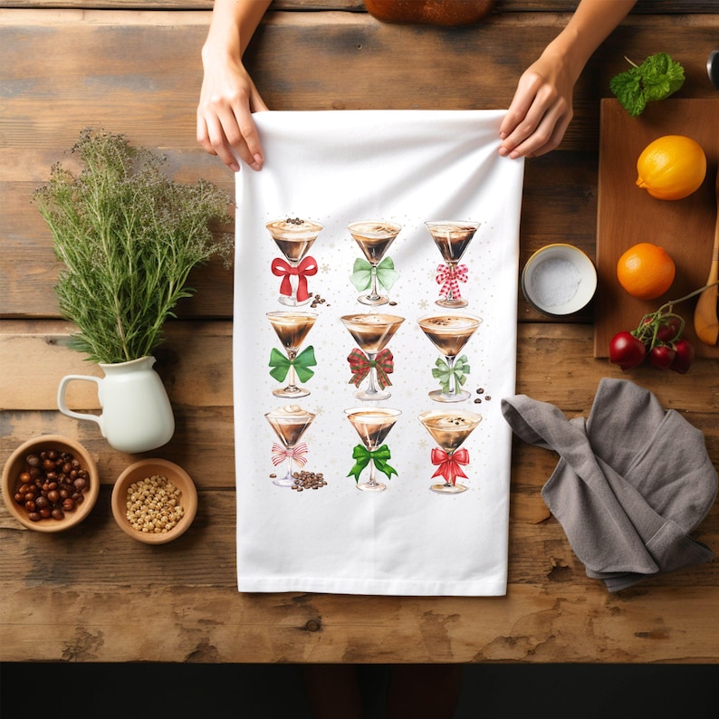 May include: White kitchen towel with a design of nine coffee cocktails decorated with red and green bows. The cocktails are in martini glasses and have a brown liquid inside.