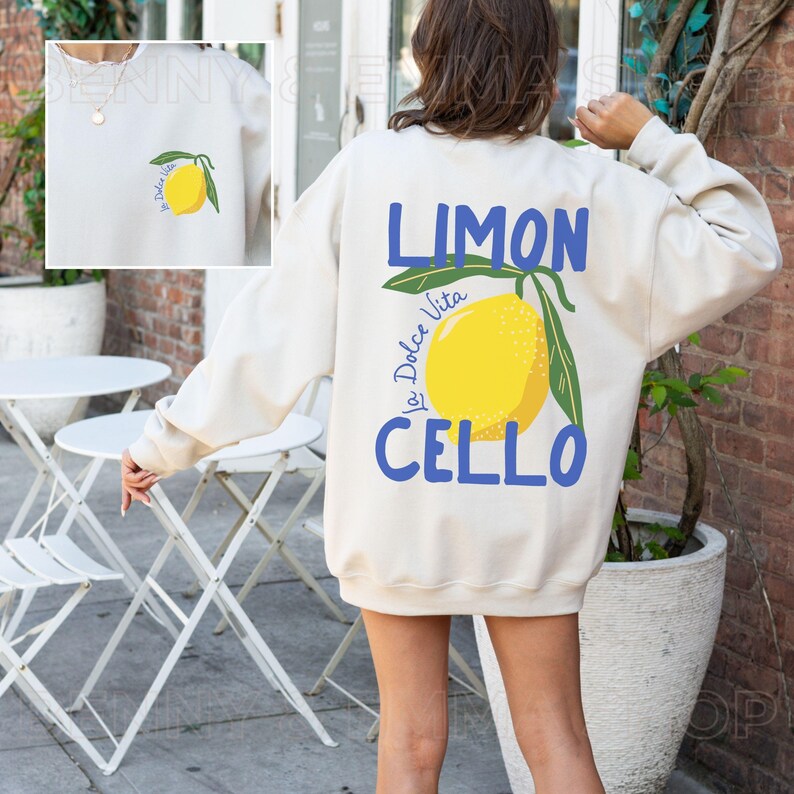 May include: A cream colored sweatshirt with a lemon graphic and the text "Limon La Dolce Vita Cello" printed on the back.