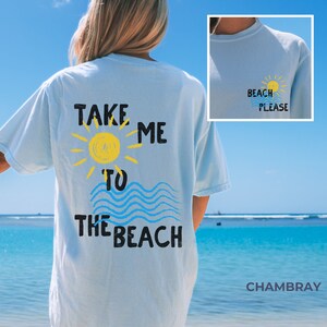 May include: Light blue t-shirt with the text "Take Me To The Beach" in black lettering. The text is accompanied by a yellow sun and blue waves. The back of the shirt has the text "Beach Please" in black lettering with a yellow sun.