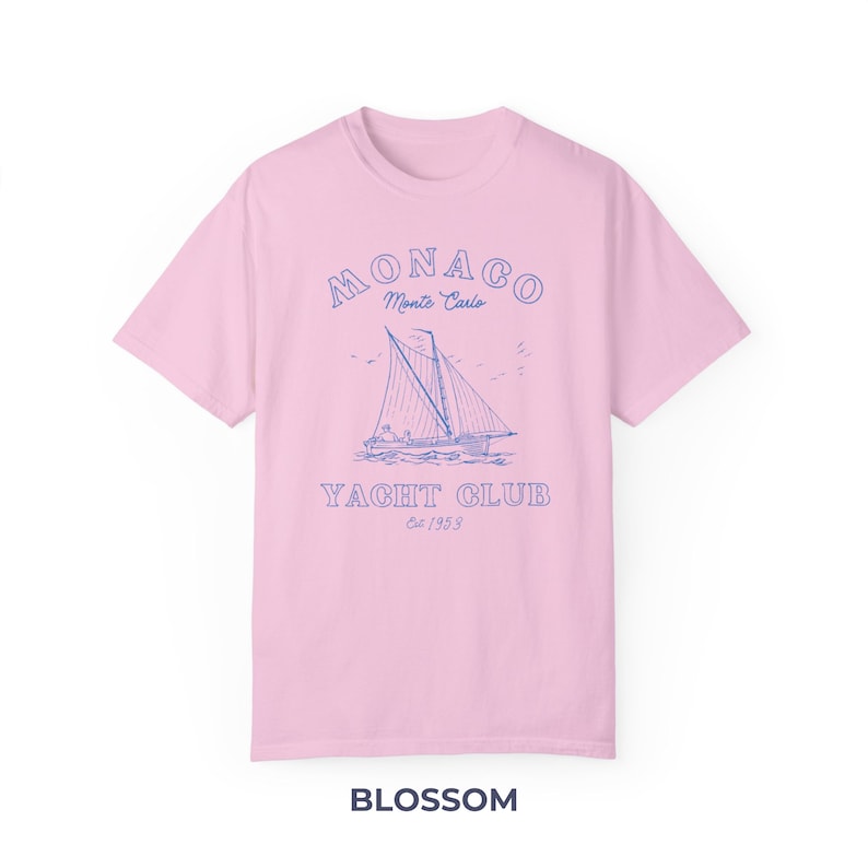 Peut inclure: Un t-shirt rose avec un graphique bleu d'un voilier et le texte "MONACO Monte Carlo YACHT CLUB Est/1953".