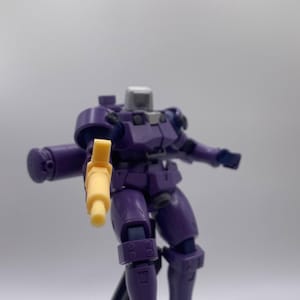 May include: A purple and gray robot toy holding a yellow gun. The robot has a detailed design with multiple joints and is posed in a dynamic action pose.