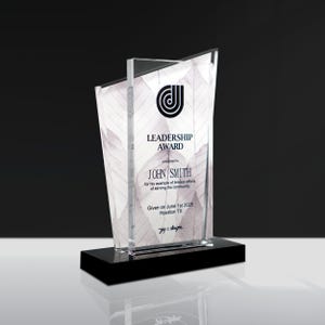 May include: A clear acrylic Leadership Award with a black base. The award features a leaf design and the text "LEADERSHIP AWARD" along with the recipient's name, date, and location. The award is approximately 10 inches tall.