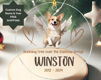 May include: Clear round glass ornament with a picture of a corgi dog with angel wings. The ornament has the text "Running Free over the Rainbow Bridge" and the name "WINSTON" with the dates "2012-2024".