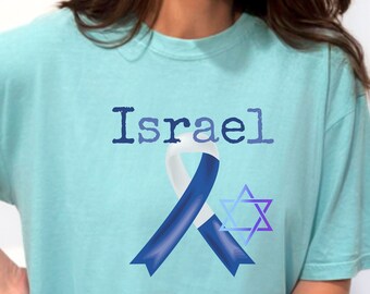 May include: A light blue t-shirt with the word "Israel" printed on the front. A blue and white ribbon with a Star of David is centred on the shirt. The shirt is called "Chalky Mint".