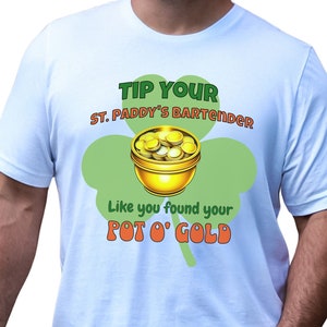 May include: White t-shirt with a St. Patrick's Day graphic. The design features a green shamrock, a pot of gold, and the text "Tip Your St. Paddy's Bartender Like you found your Pot O' Gold."