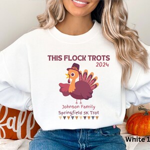 May include: White sweatshirt featuring a cartoon turkey wearing a hat, with the text "THIS FLOCK TROTS 2024". Below the turkey is "Johnson Family Springfield 5K Trot". A Thanksgiving-themed design.