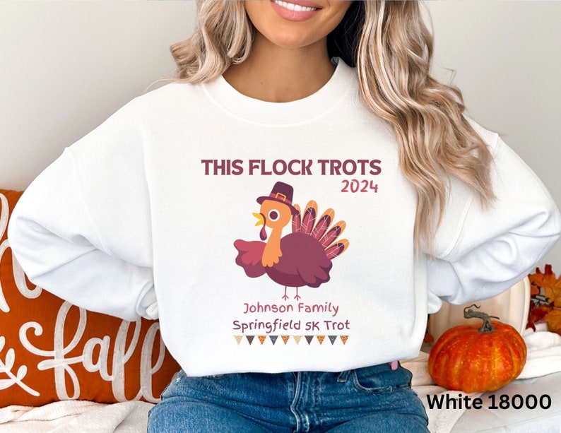May include: White sweatshirt featuring a cartoon turkey wearing a hat, with the text "THIS FLOCK TROTS 2024". Below the turkey is "Johnson Family Springfield 5K Trot". A Thanksgiving-themed design.