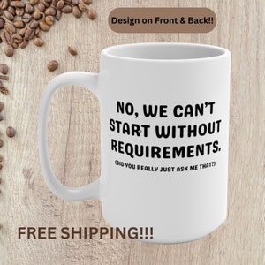 May include: White ceramic coffee mug with black text that reads "NO, WE CAN'T START WITHOUT REQUIREMENTS. (DID YOU REALLY JUST ASK ME THAT?)". The mug is on a woodgrain surface with coffee beans scattered around it. Free shipping is indicated in the text below the mug.