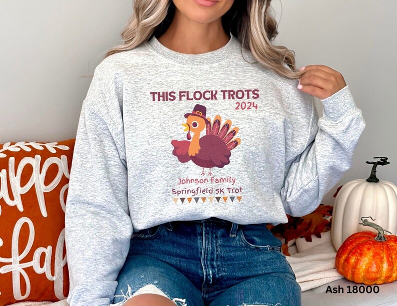 May include: Light grey sweatshirt featuring the text "THIS FLOCK TROTS 2024" and a cartoon turkey wearing a hat. The sweatshirt also includes the text "Johnson Family Springfield 5K Trot".
